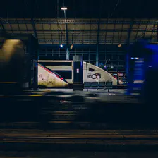  A FRET train is moving (blurred) on the foreground, leaving only two "head" of TGV on far platforms.  