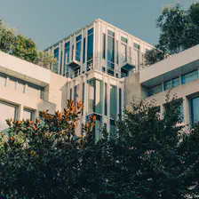A square-ish building in Paris with lots of vegetation around and on it. 