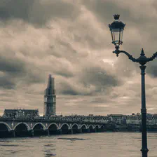 A stone bridge called Pont de Pierre crossing the Garonne in Bordeaux. You can see a twin public light on the right. On the background, you can see a tower surrounded by scaffolding for repair. 
https://www.flickr.com/photos/ztec/53412369313/
Albums: www